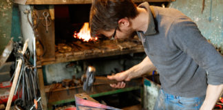 Blacksmith forging red-hot metal with hammer. \
