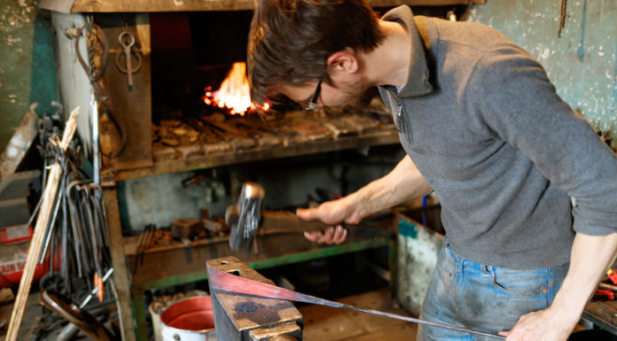 Blacksmith forging red-hot metal with hammer. \